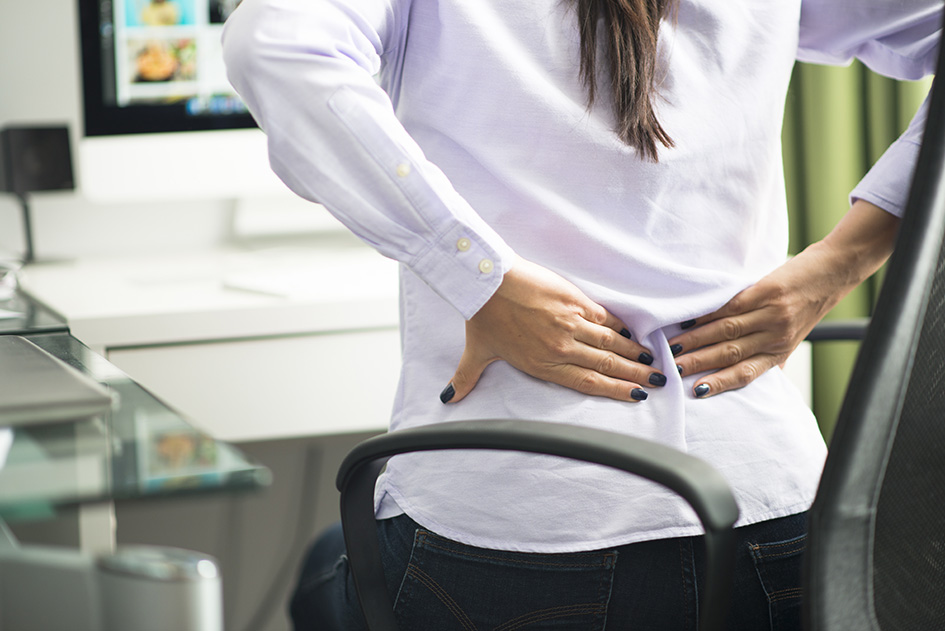 a seated woman massages her lower back