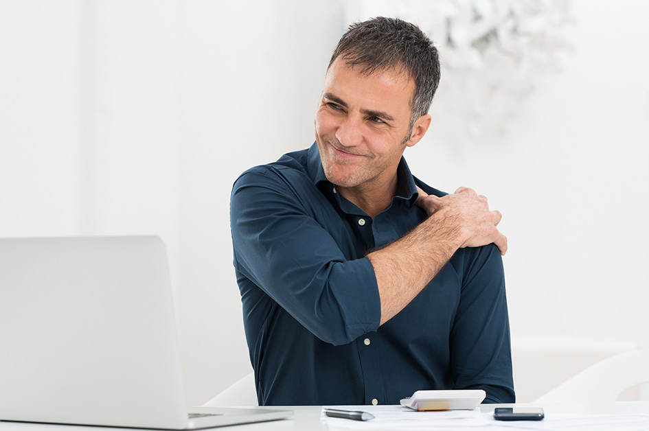 a man sitting massages his painful shoulder